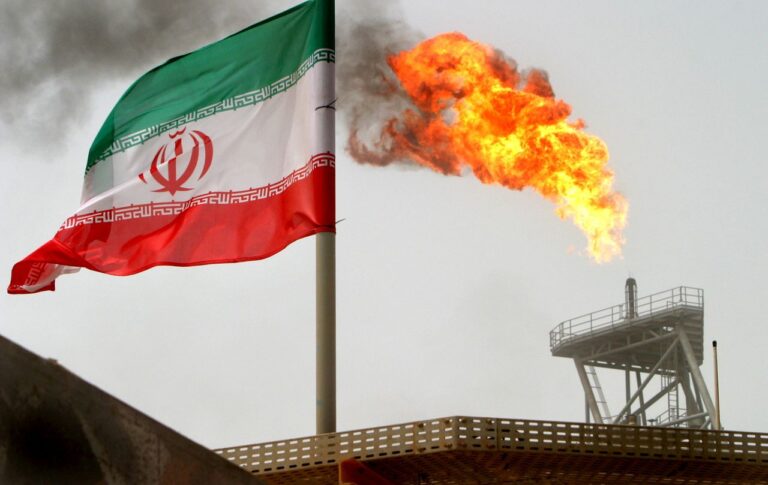 A gas flare on an oil production platform is seen alongside an Iranian flag in the Gulf July 25, 2005 [FILE]