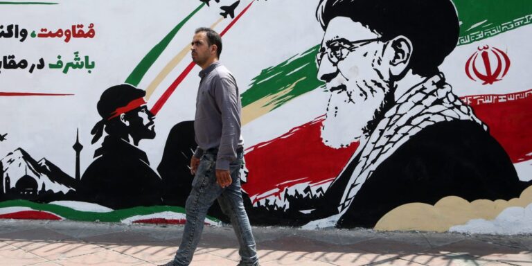 A man walks in front of a wall mural in Tehran, Iran, on August 6, 2026