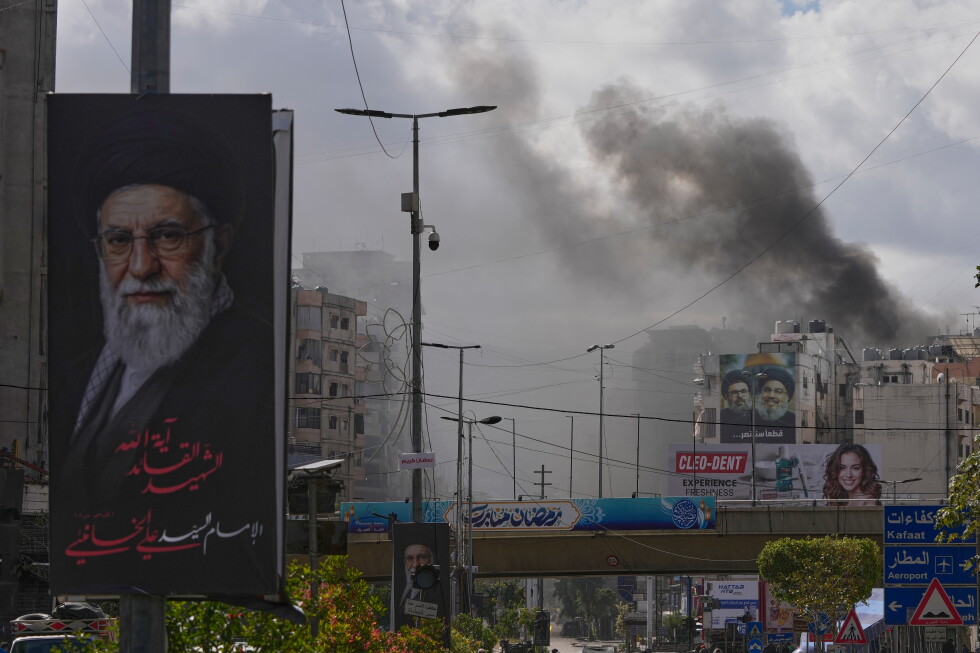 A portrait of Iran's late Supreme Leader Ayatollah Ali Khamenei, left, is seen, as smoke rises following an Israeli