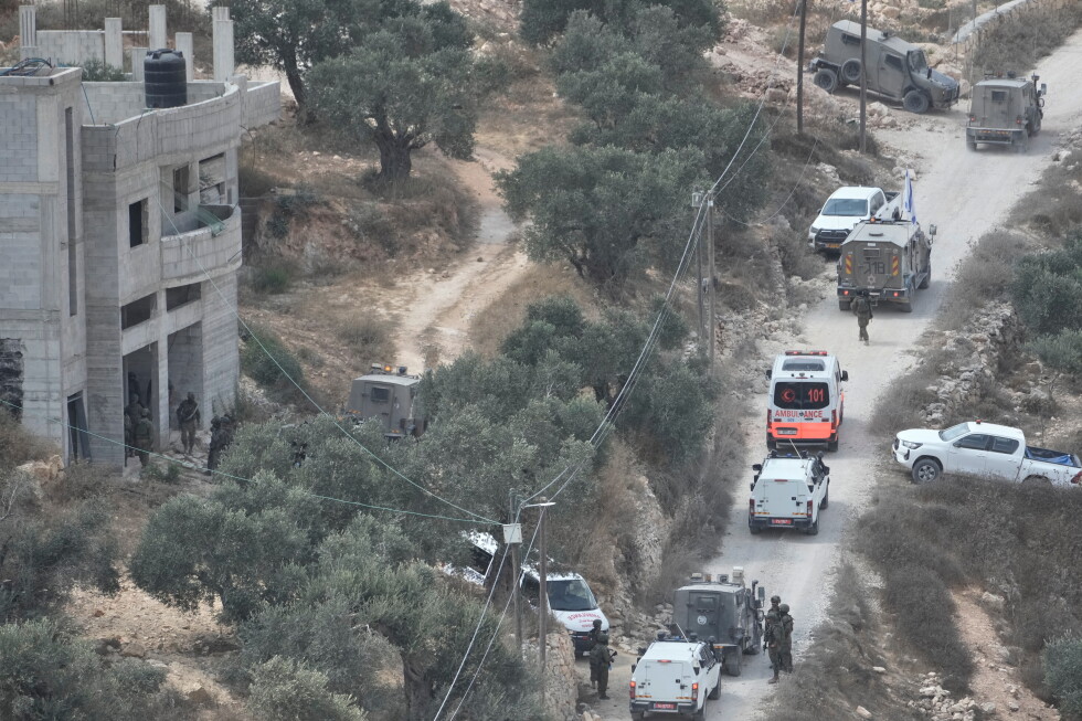 Israeli soldiers secure a building under construction as ambulances evacuate injured Palestinians following an attack by
