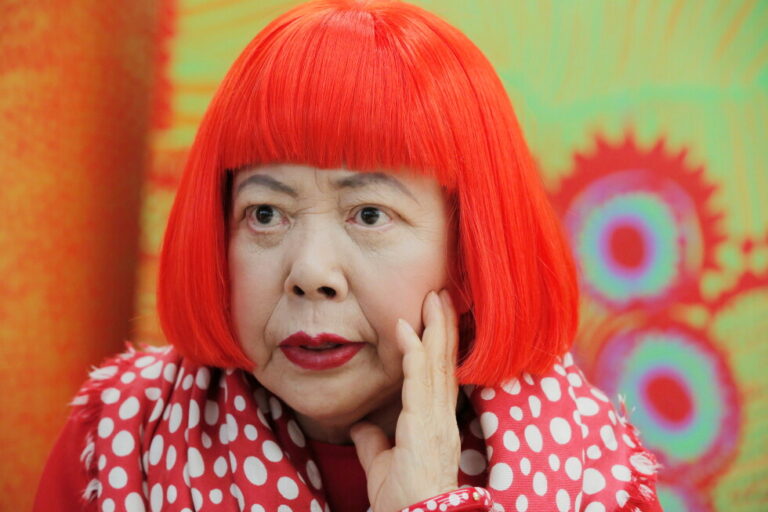 Japanese avant-garde artist Yayoi Kusama, wearing a bright red wig and a Louis Vuitton polka dot scarf, speaks during an