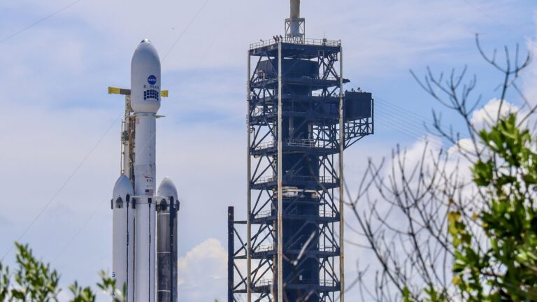 A triple core rocket with one sooty booster stands at a launch pad