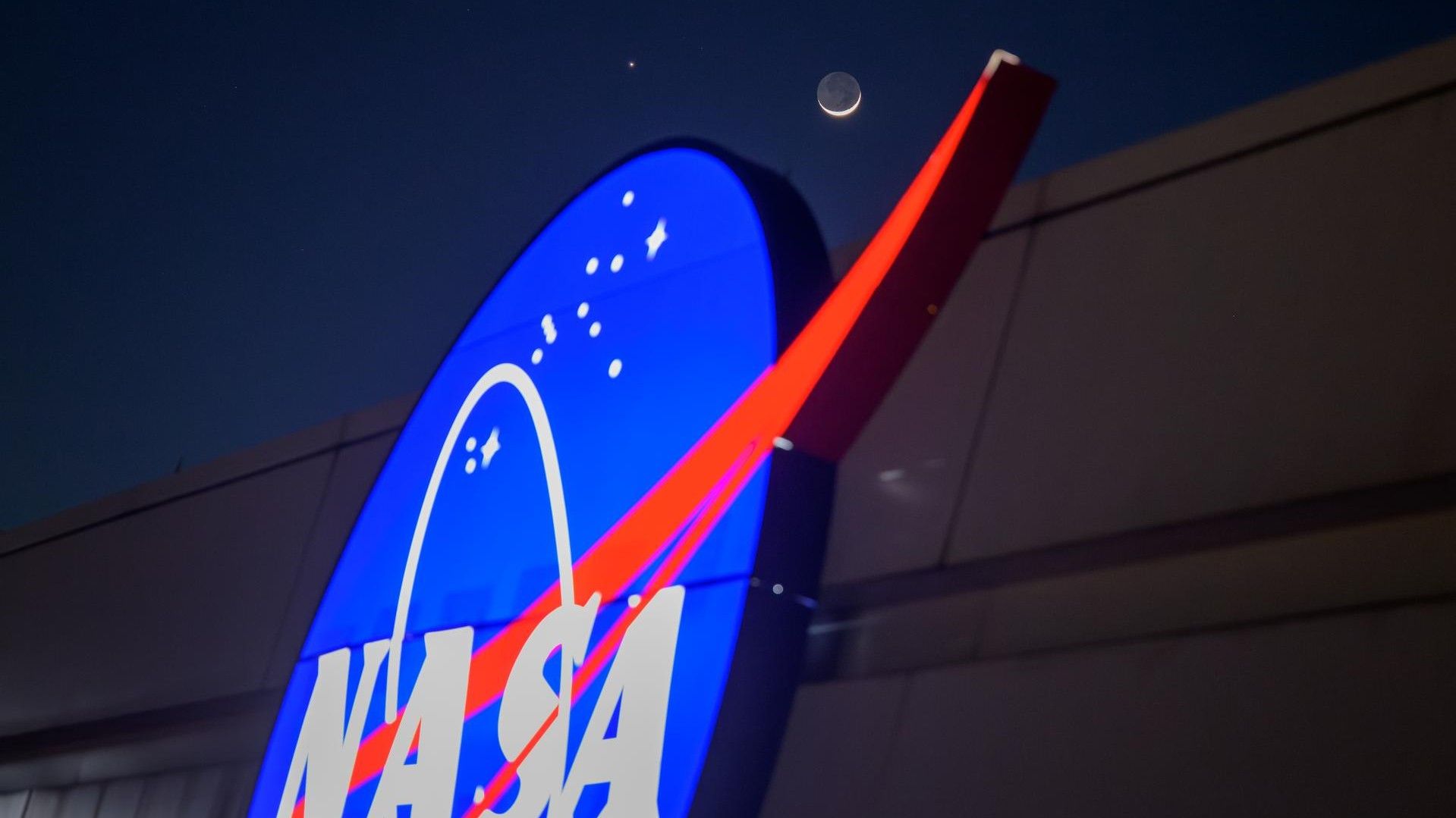 The crescent moon and Venus shine in the night sky above the NASA