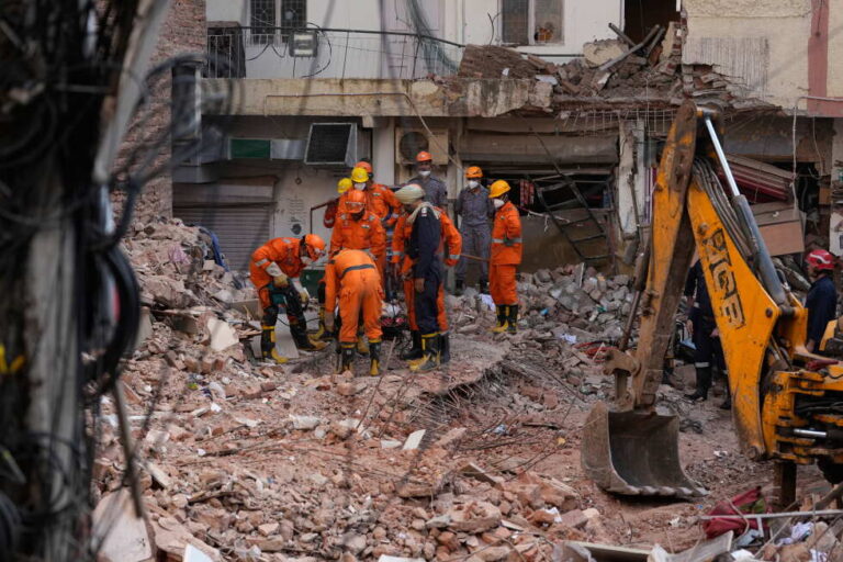 Rescue workers continue to search for people trapped under the debris of a collapsed building in New Delhi, India, Monday