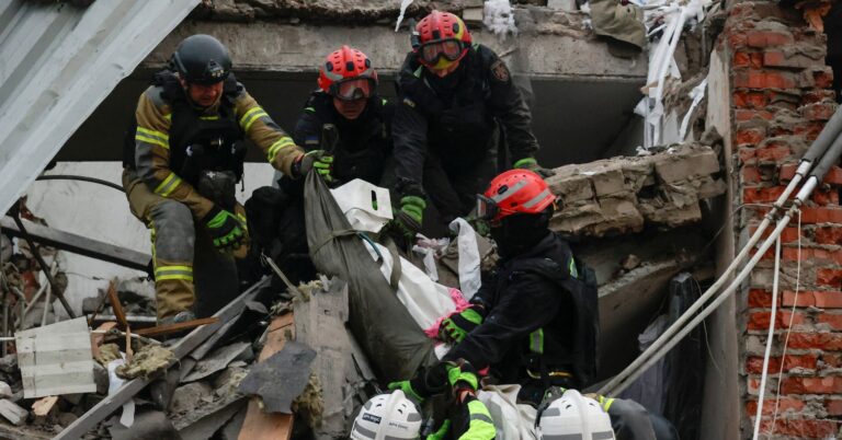 Rescuers carry the body of a killed person found under debris of a sewing factory which was hit by a Russian airstrike, amid