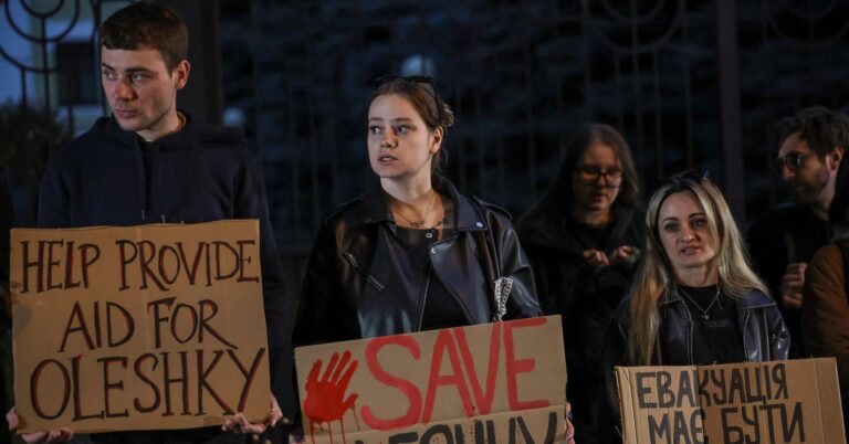 People hold posters as they participate in a rally demanding the establishment of a humanitarian corridor to evacuate