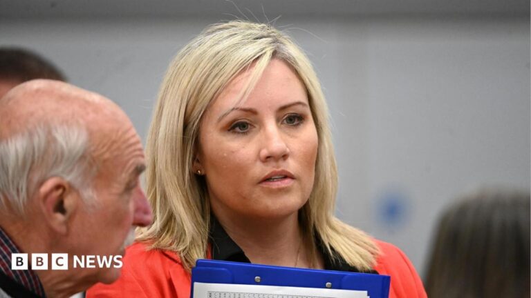 Diane Forsythe, who has long, blonde hair and holds a blue clipboard