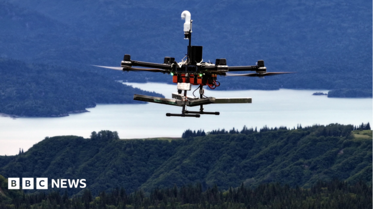 A Rainmaker drone flies over forests and a lake in Alaska