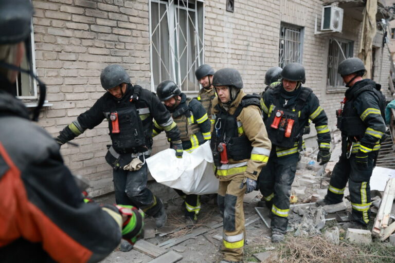 Rescue workers carry a body after pulling from the rubble of a residential building destroyed by a Russian airstrike in