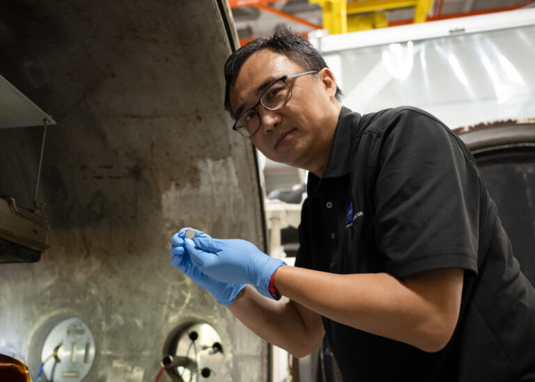 Yi Lin, SPEARS testing and research lead at NASA Langley, holds one of the small coin-cell batteries that had just undergone